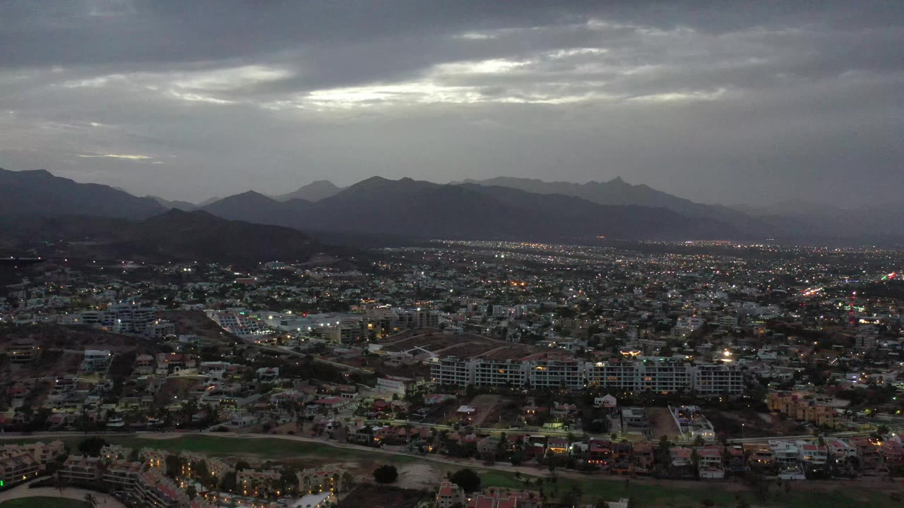 Aerial city grid with glowing lights beneath heavy clouds