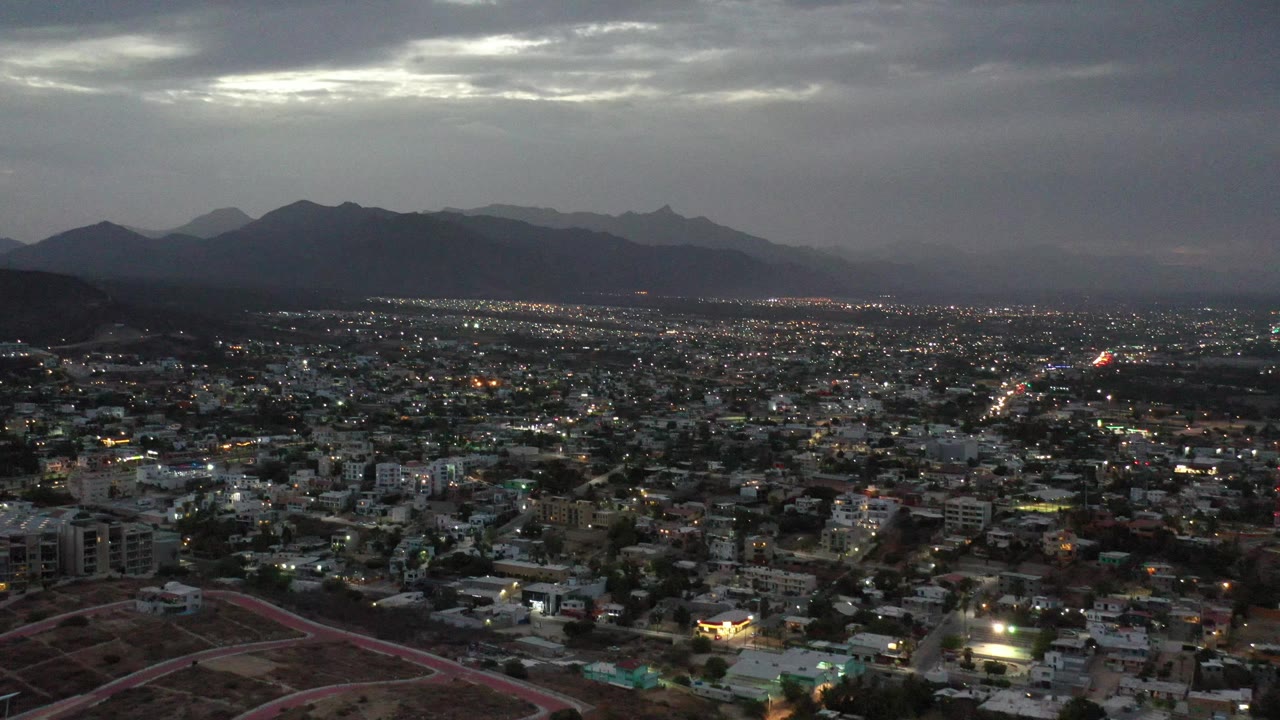 Aerial cityscape with dusk lights and mountains.