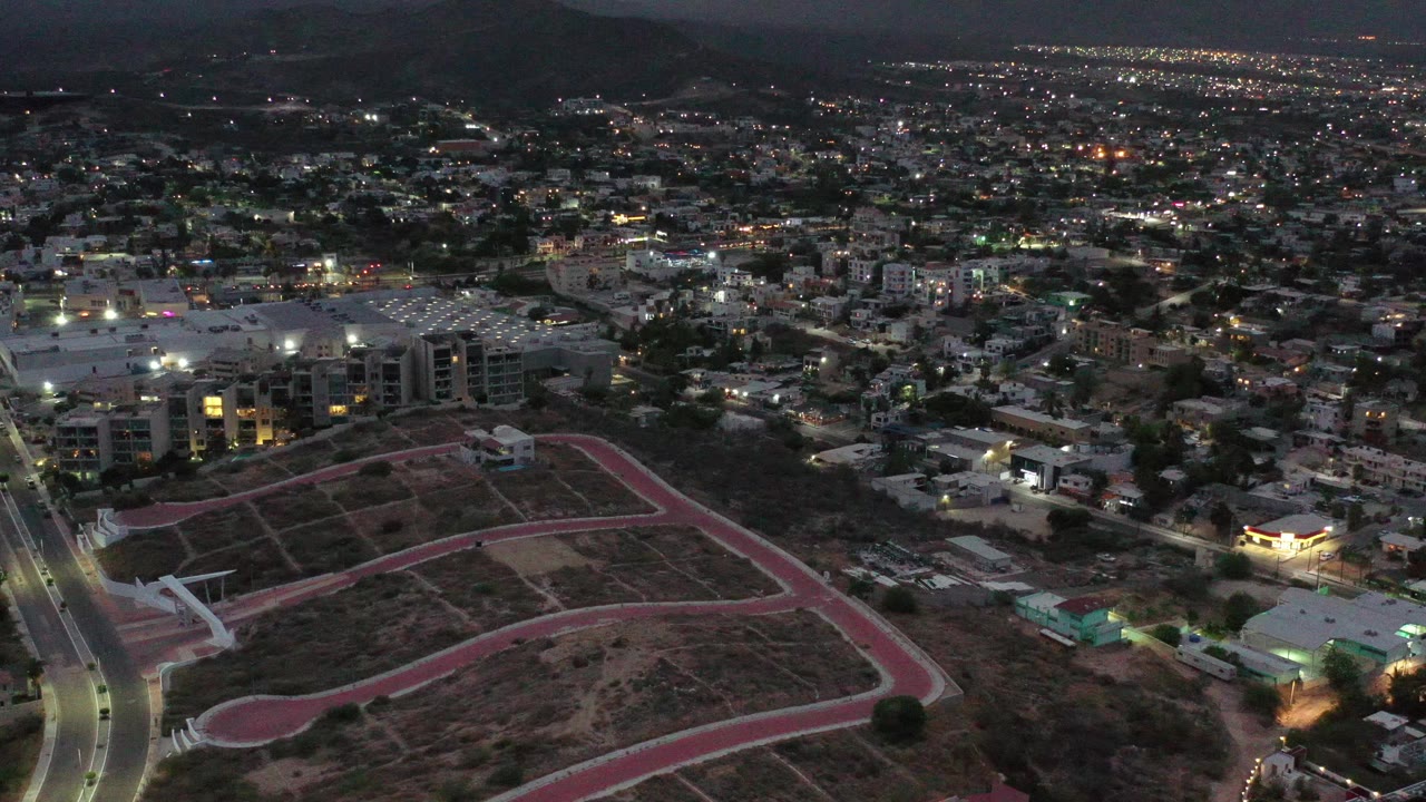 City lights spread below a dark mountain ridge at night.