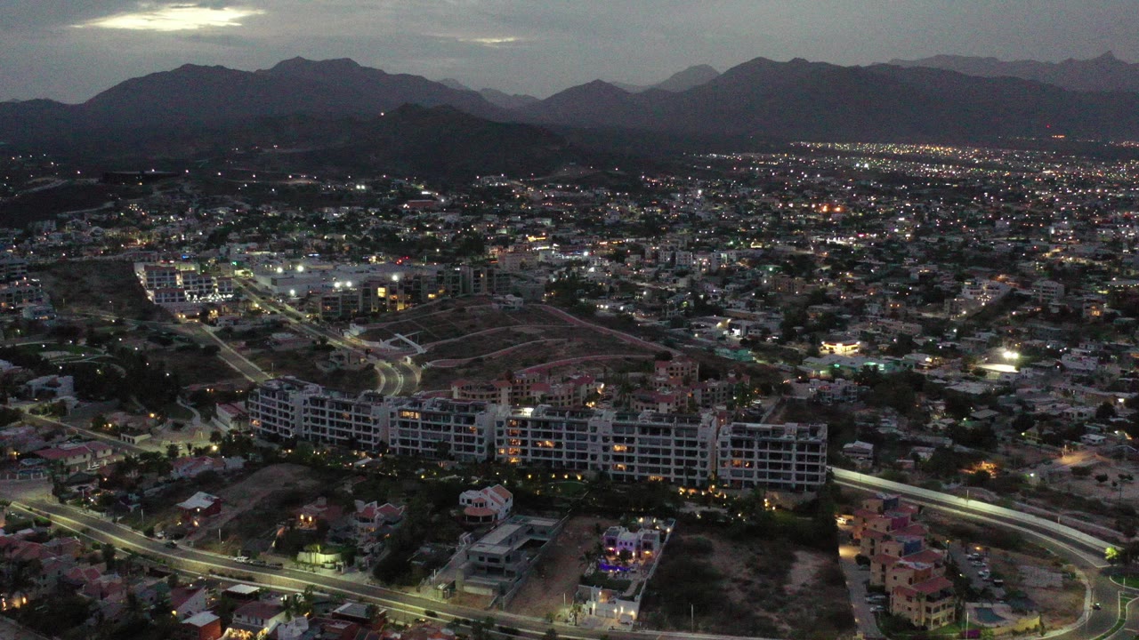 Dusk aerial view over a city with mountains beyond.