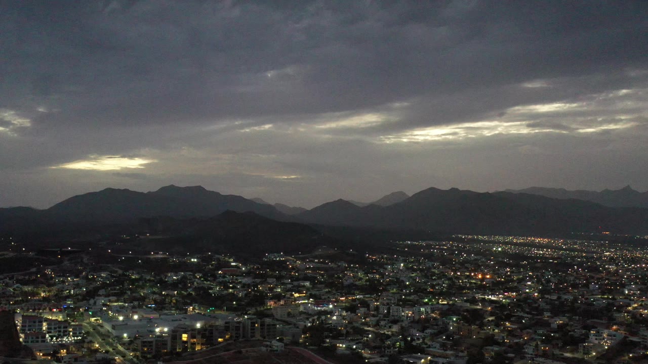 Night city lights with a bright opening in the cloud cover.