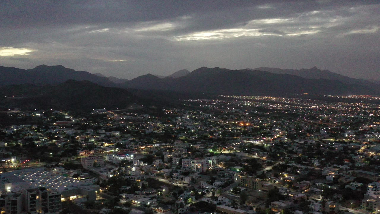 Wide dusk city view with mountains and clouded sky