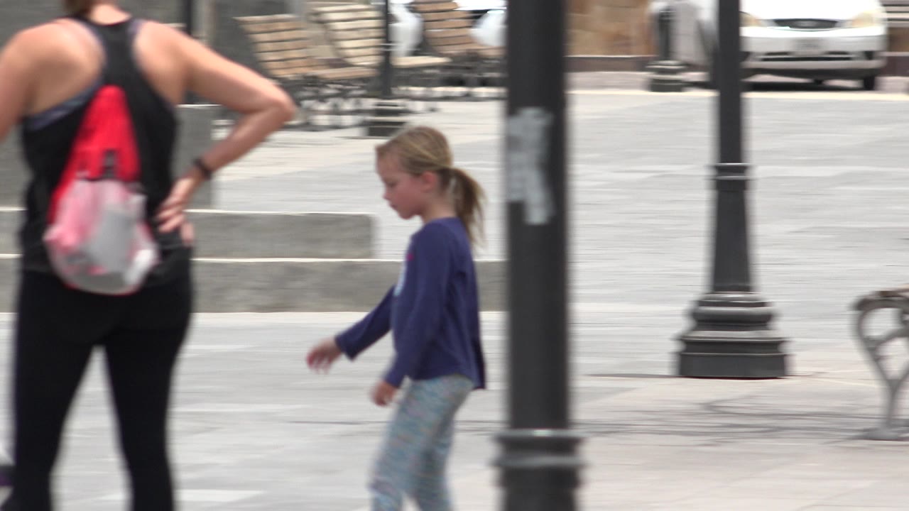Woman with drawstring backpack and young girl in a public square.