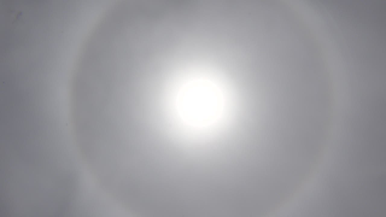 Bright white sun centered in a hazy Los Cabos sky, with a faint circular halo and no visible people.