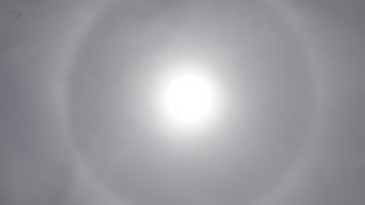 Blown-out sun surrounded by a diffuse ring in a muted gray sky.