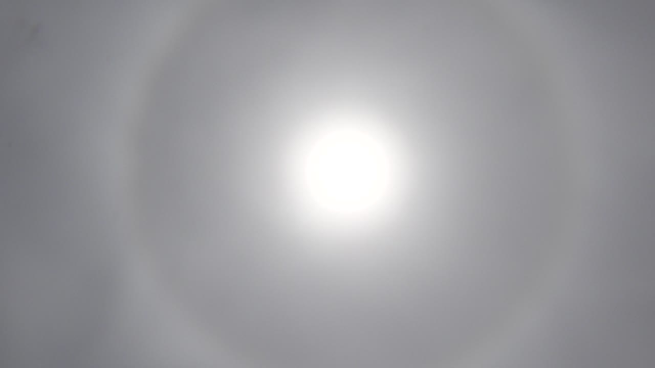 White sun glow holds near the center of a softly clouded Los Cabos sky, with no visible people.