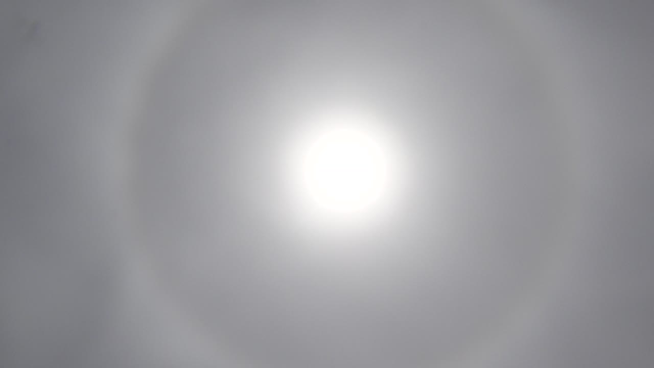 Bright circular sun bloom in hazy sky.