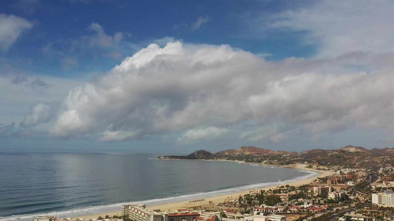 Broad beach coastline under layered white and gray clouds.
