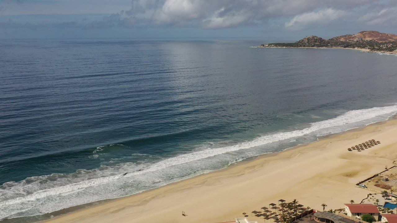 Elevated view of calm ocean waves reaching an empty sandy beach.
