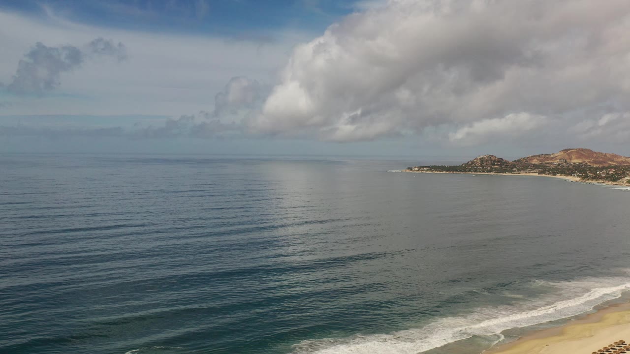 Ocean and distant Los Cabos shoreline beneath thick clouds