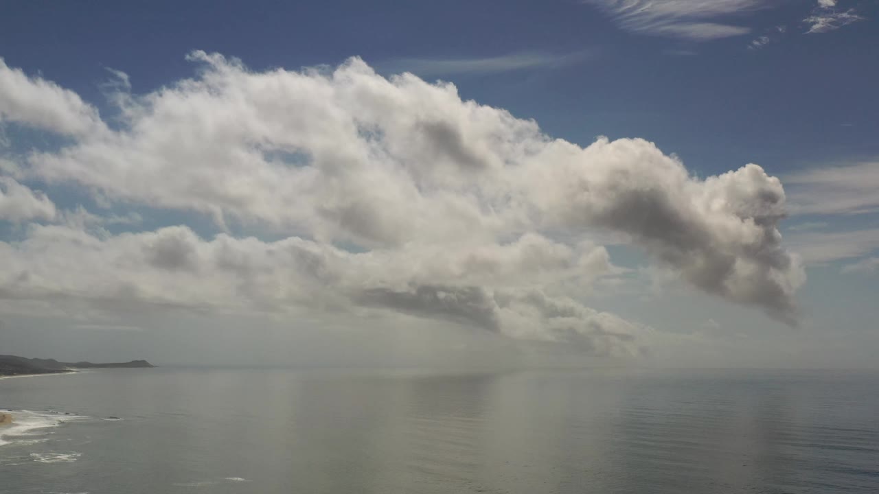 Los Cabos, Mexico coastal sky view with layered white and gray clouds hanging over calm water, with no visible people.