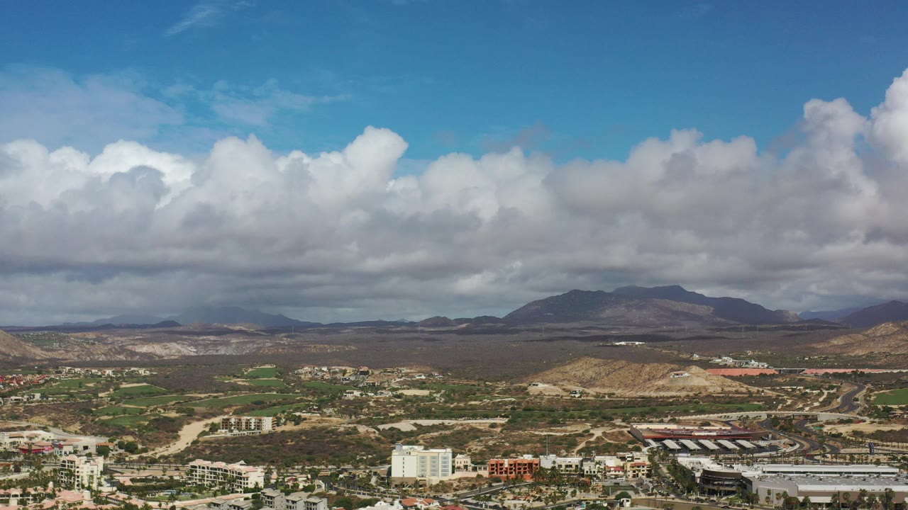 Cloudy mountain horizon with town structures and roads below.