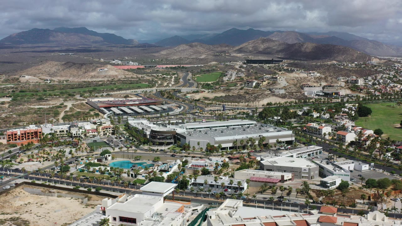 Aerial view of business park, roads, hills, and mountains under cloudy sky