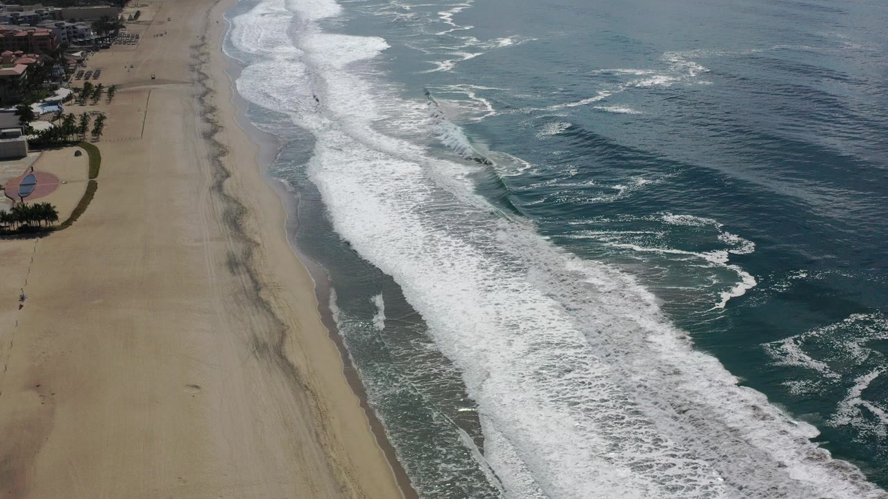 Aerial view of sandy beach and breaking ocean waves