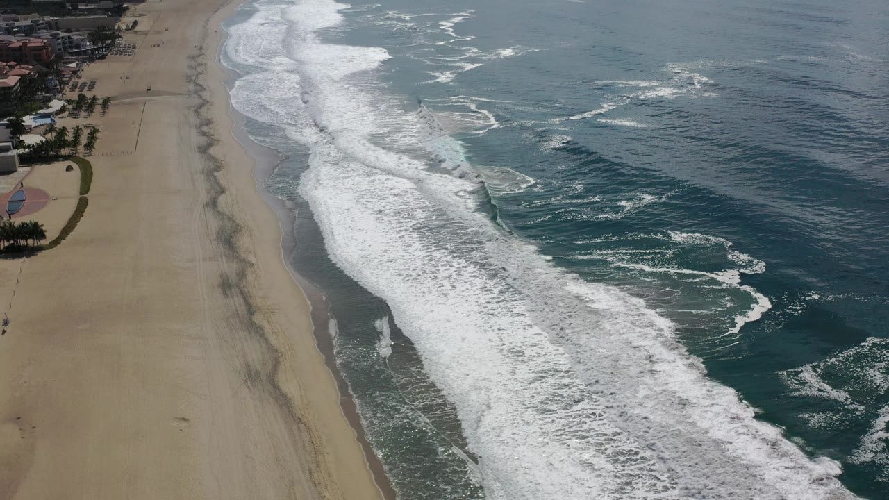 White surf bands beside a quiet sandy beach