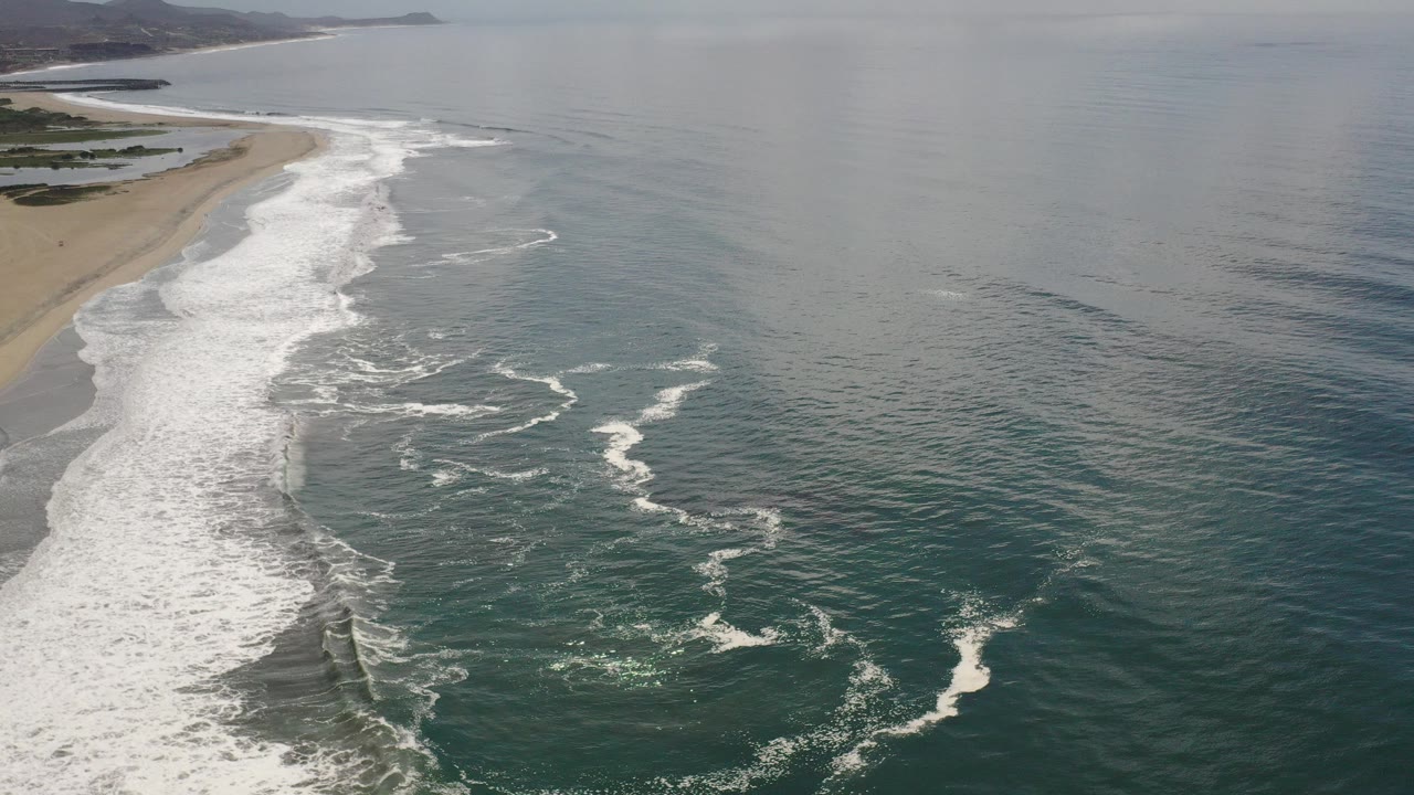 Aerial view of waves breaking beside a sandy beach