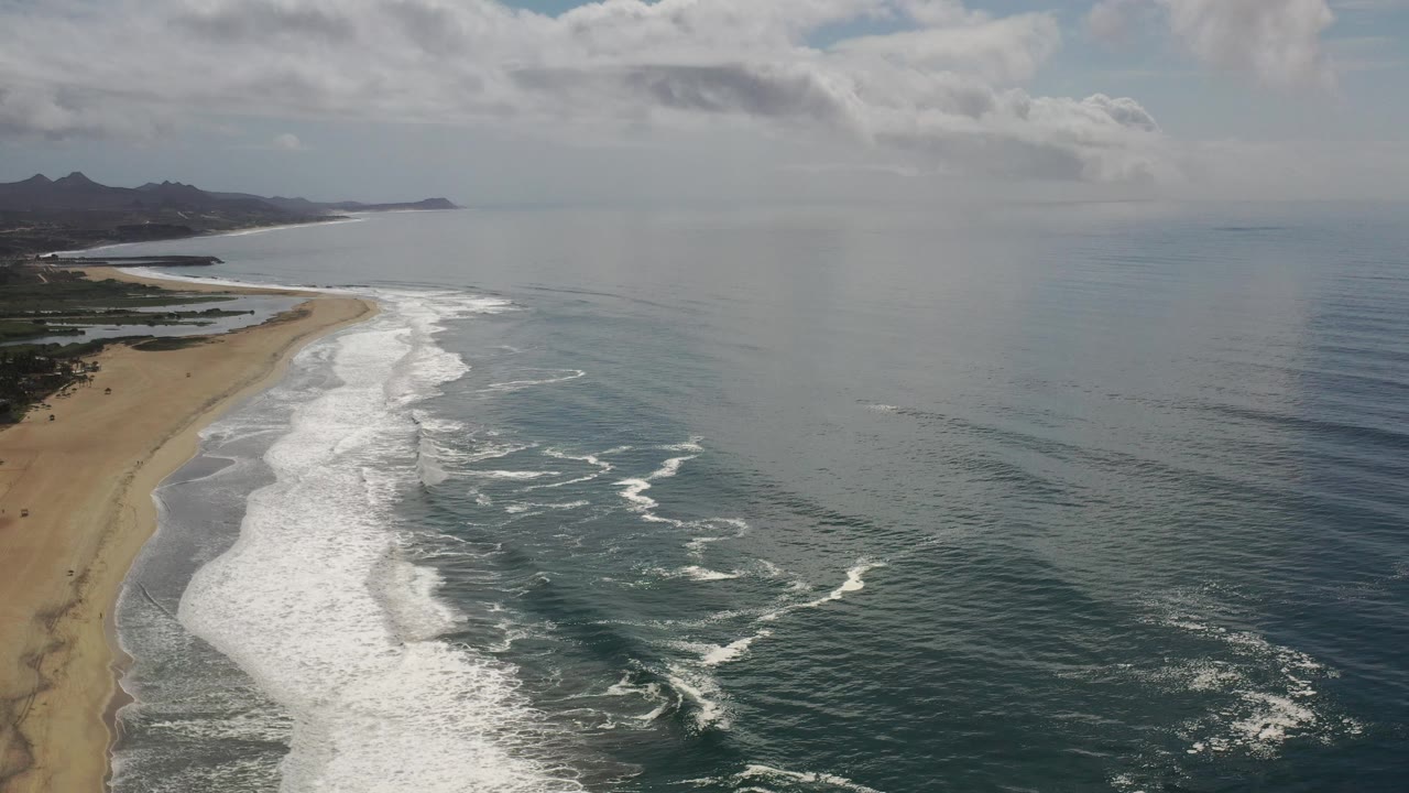 Aerial beach and ocean view with bands of foam near the shoreline.