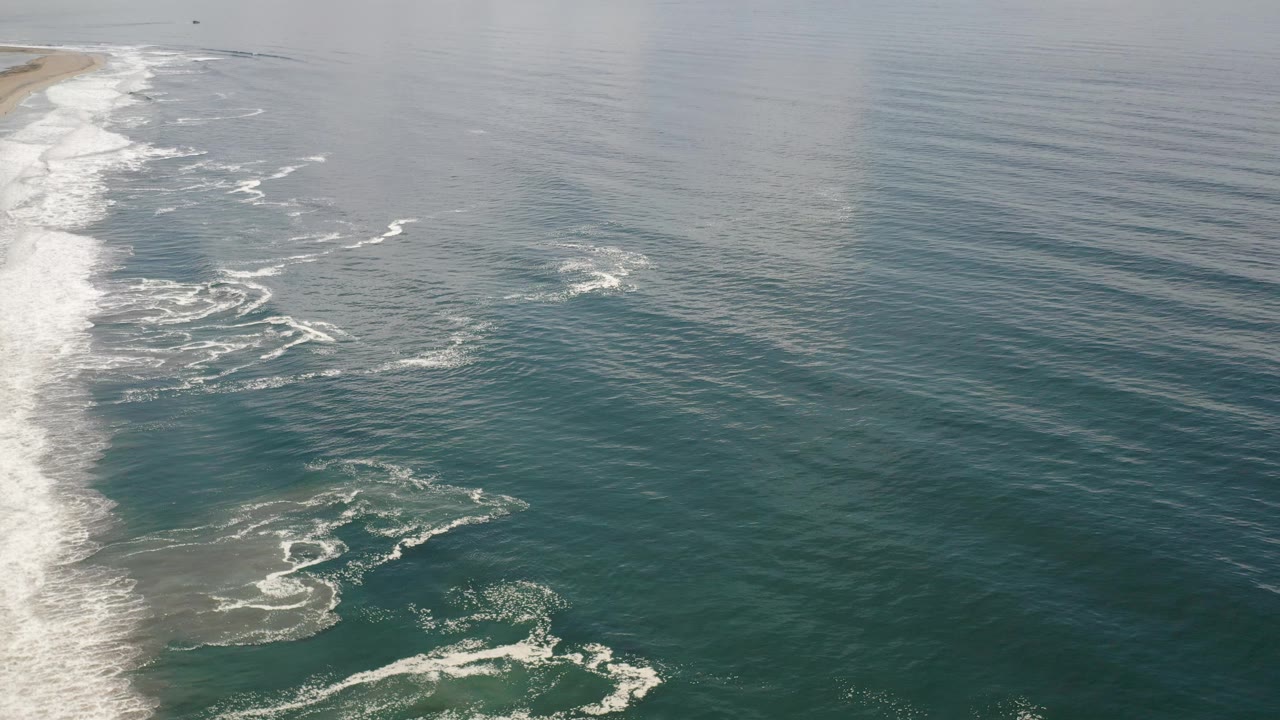 Aerial coastline view with surf line and calm offshore water