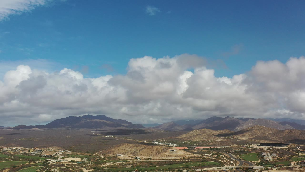 Broad mountain vista with white clouds and settlement below