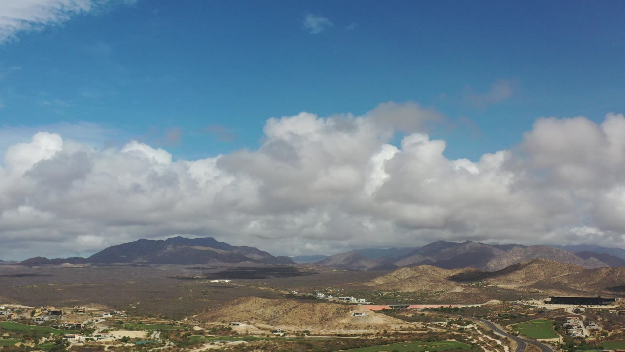 Cloudy blue sky over dry hills and distant mountains