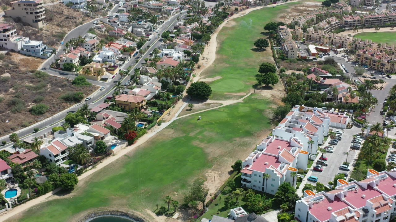 Aerial view of a golf course beside residential buildings and roads.