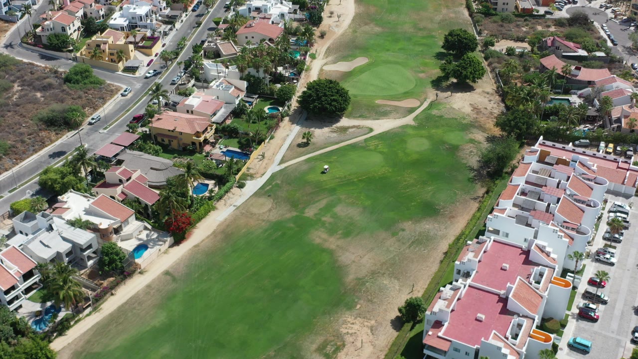 Aerial view of green field beside residential houses and a road.