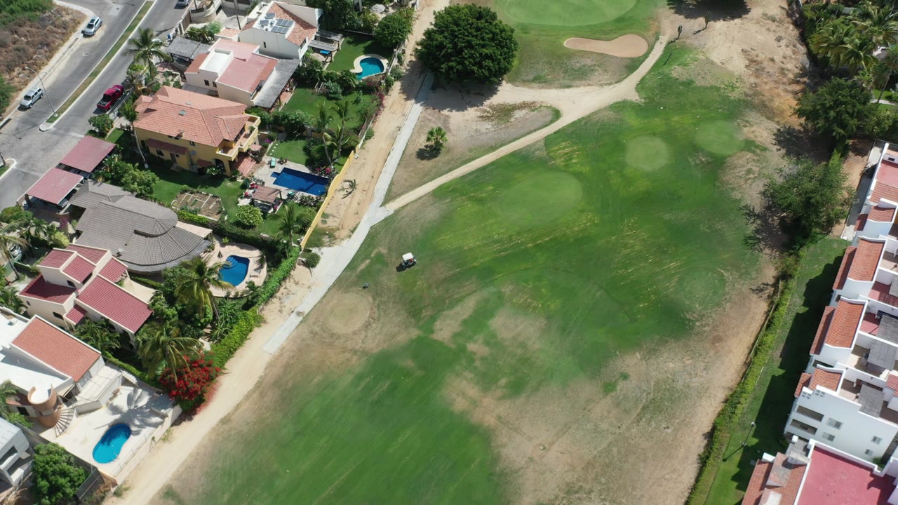 Overhead view of homes, pools, road, and golf fairway.