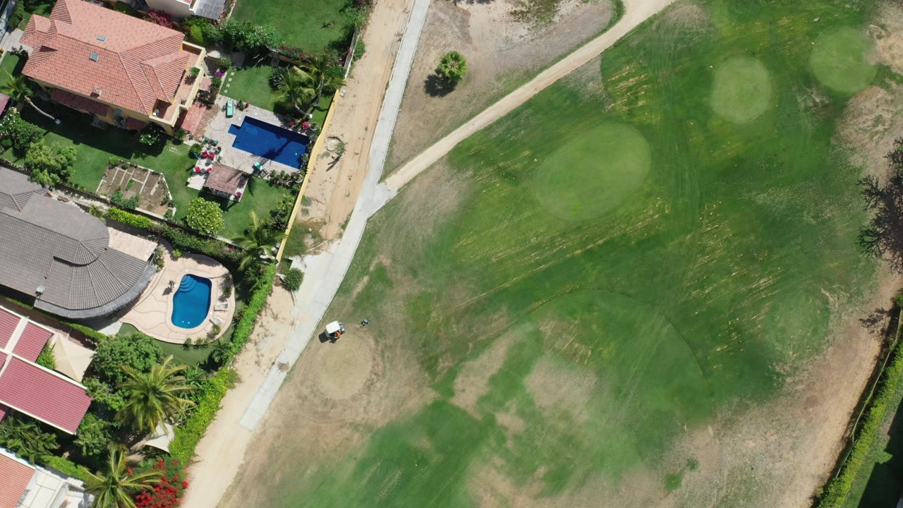 Overhead golf course beside large houses and swimming pools.