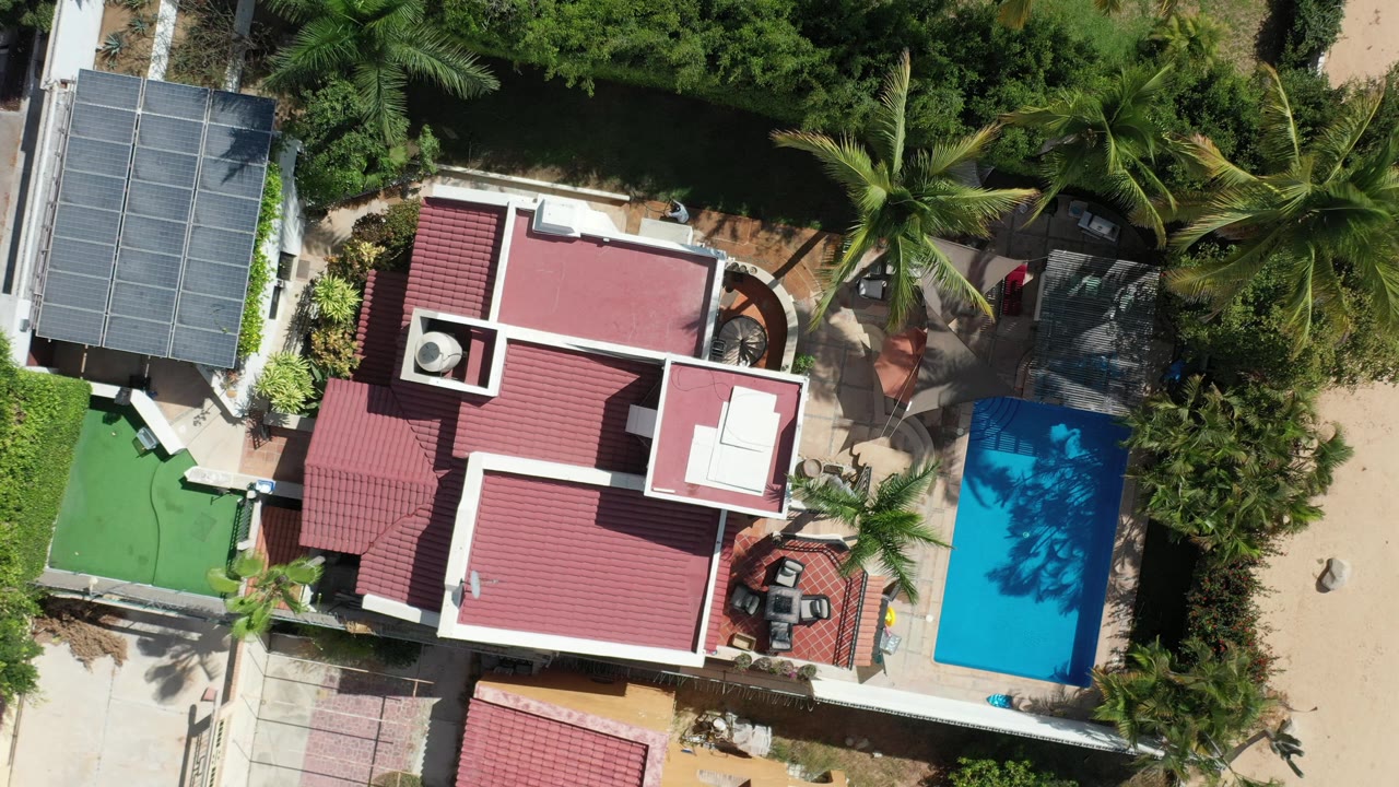 Aerial view of a private house with pool beside dense greenery.