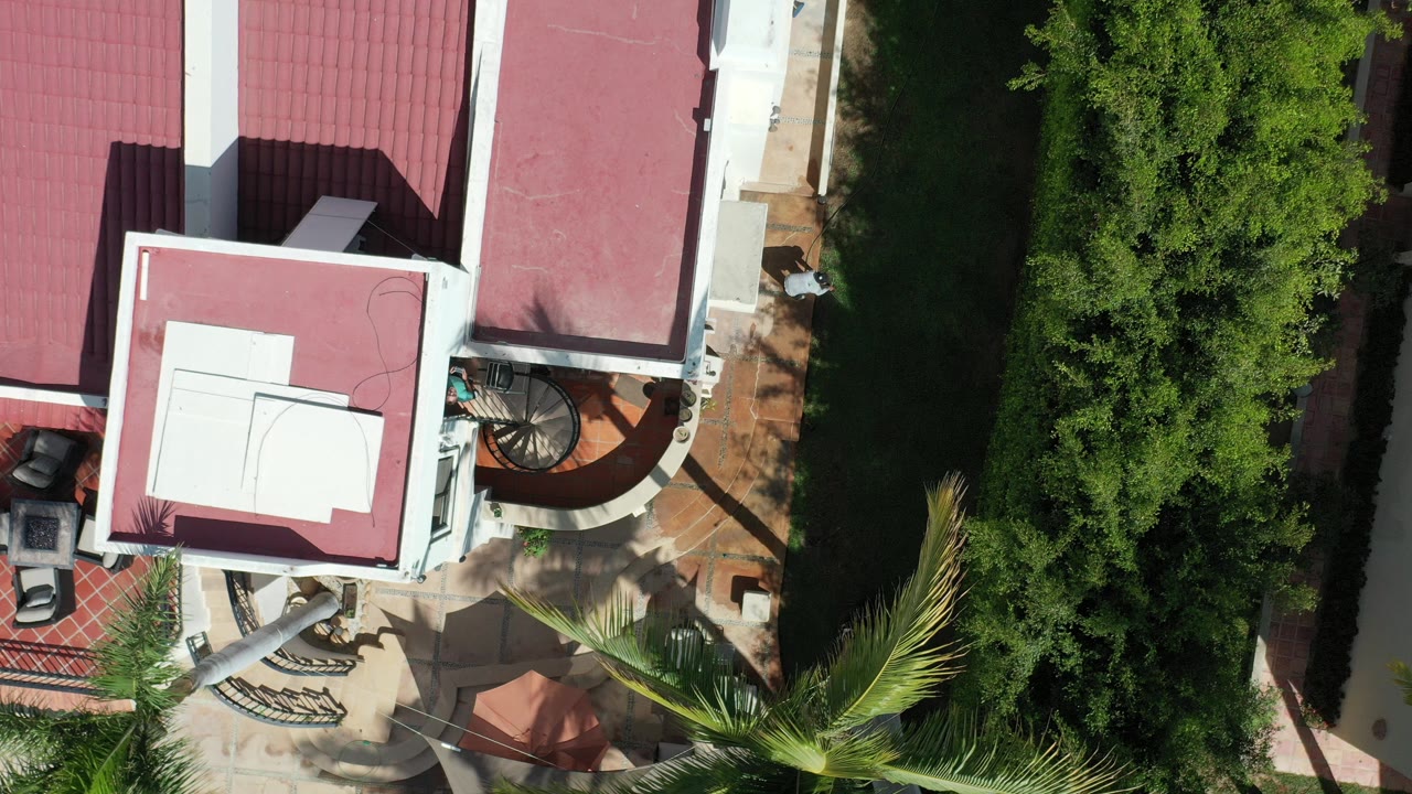 Overhead view of a white home with red roofs and green trees.