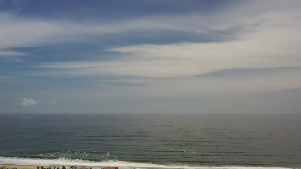 Blue ocean and white surf under layered clouds
