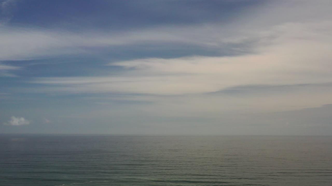 Ocean horizon under layered white and gray clouds