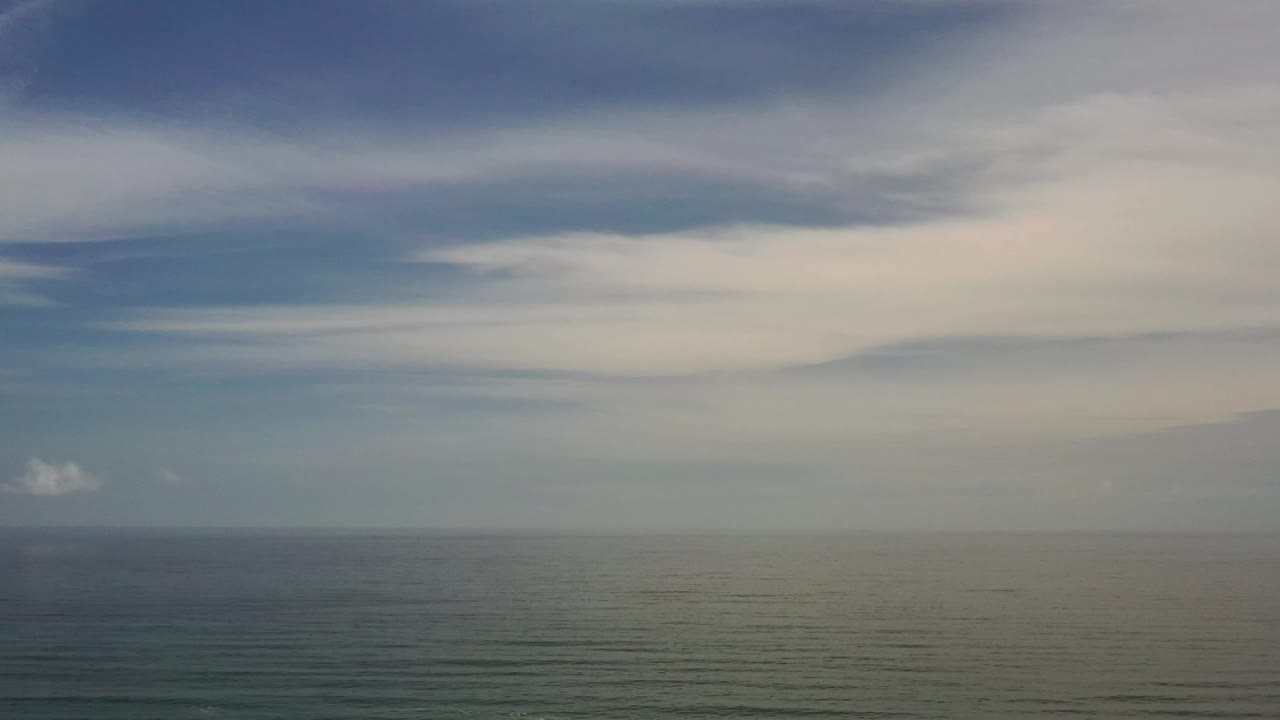 Los Cabos sea surface sits below a straight horizon and pale layered clouds, with no visible people.