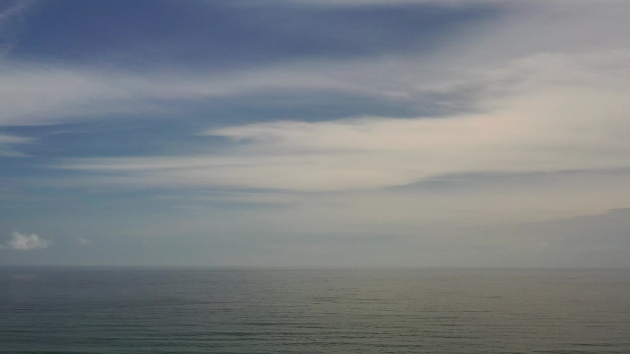 Wide ocean and clouded sky with muted light.