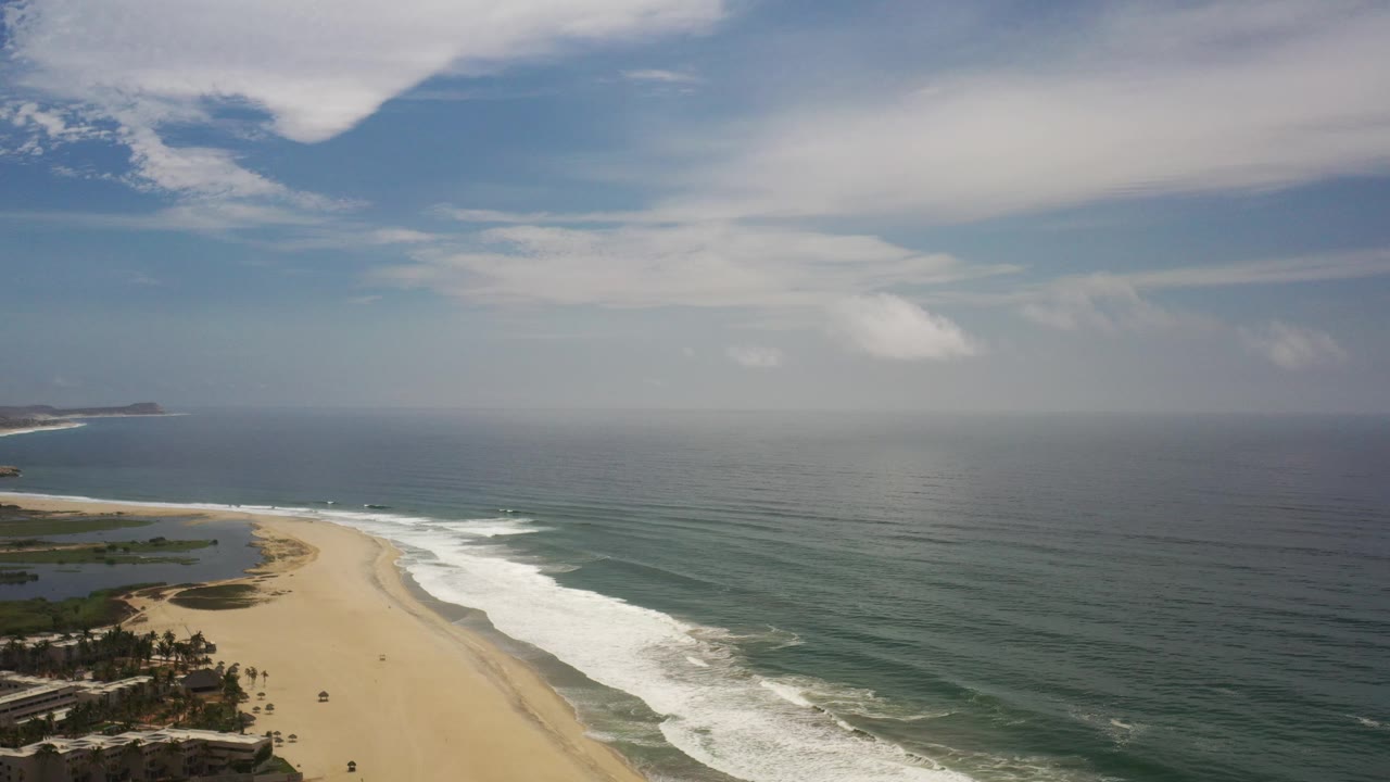 Sandy coastline and calm ocean seen from above.