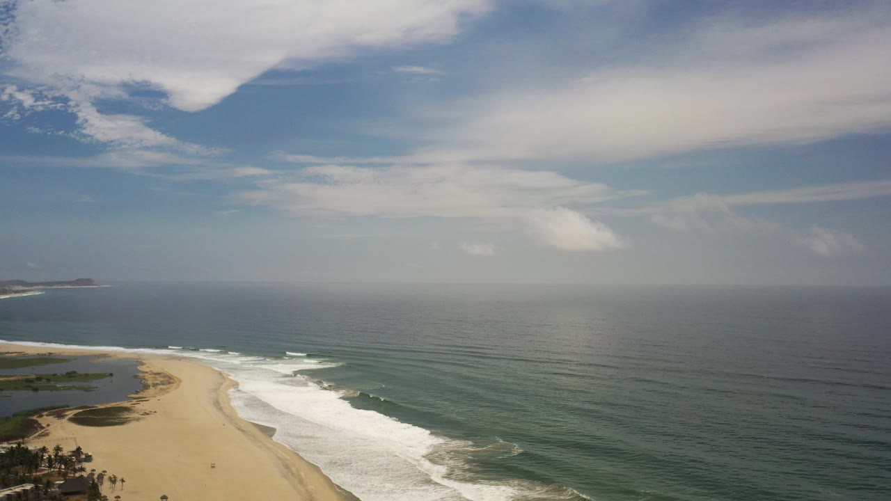 Beach and ocean under a layered cloudy sky.