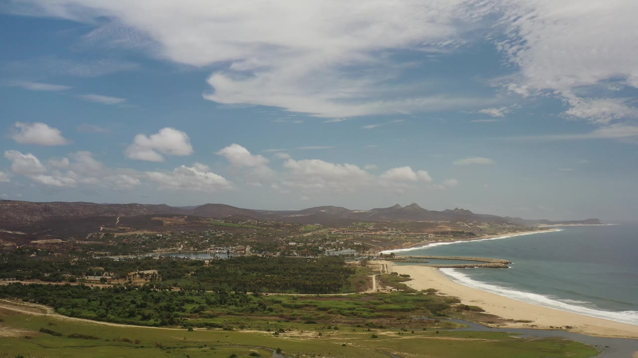 High coastal view with beach, pier or breakwater, ocean, and inland settlement.