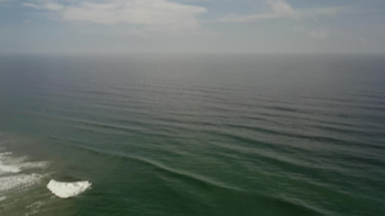 Green ocean swells with a small white break near the lower left.