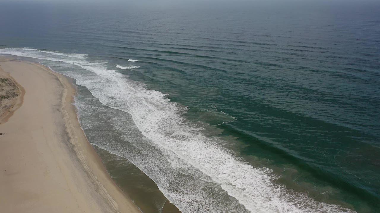 Wide ocean surface with waves approaching an empty beach