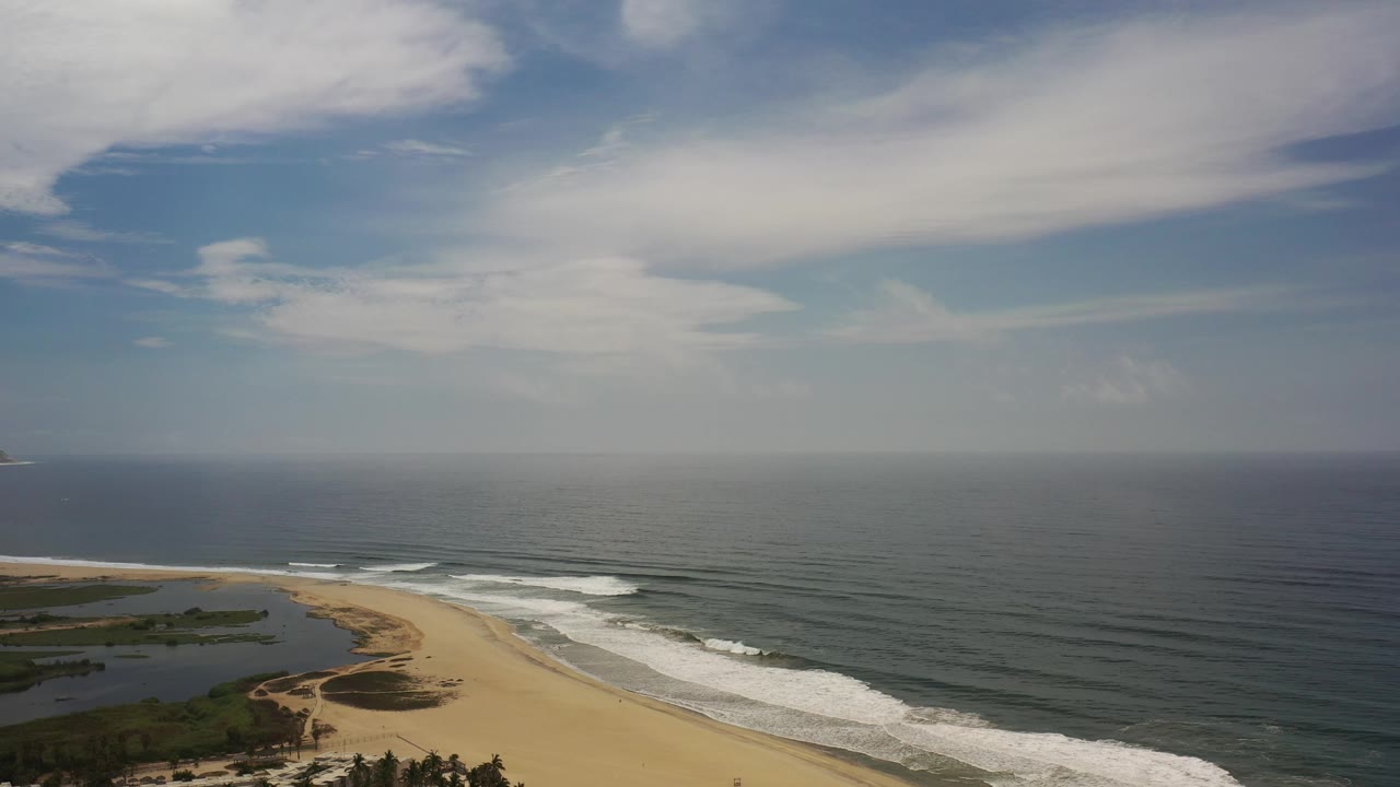 Wide beach and ocean horizon under layered clouds.
