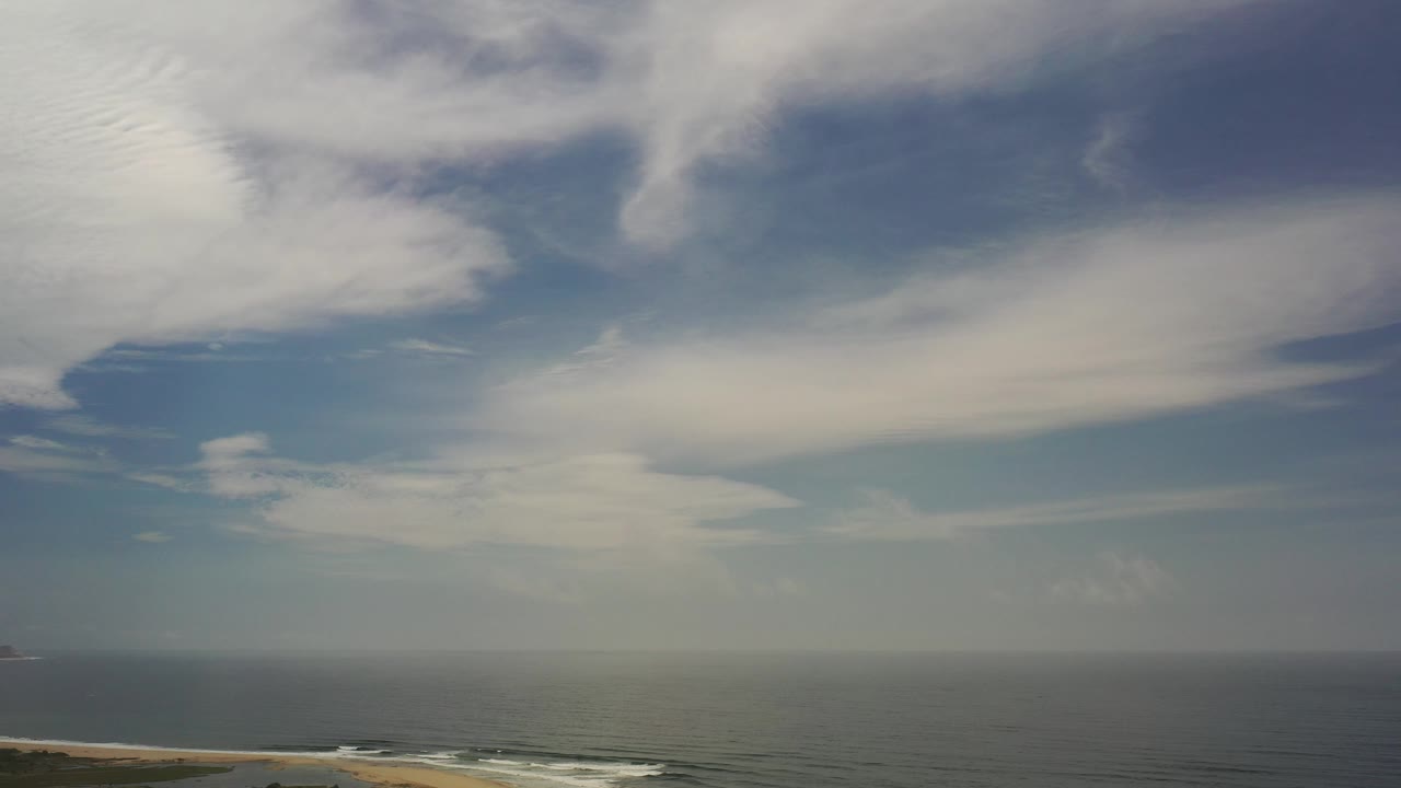 Wide sea and sky view with a low coastline and distant object near the horizon.