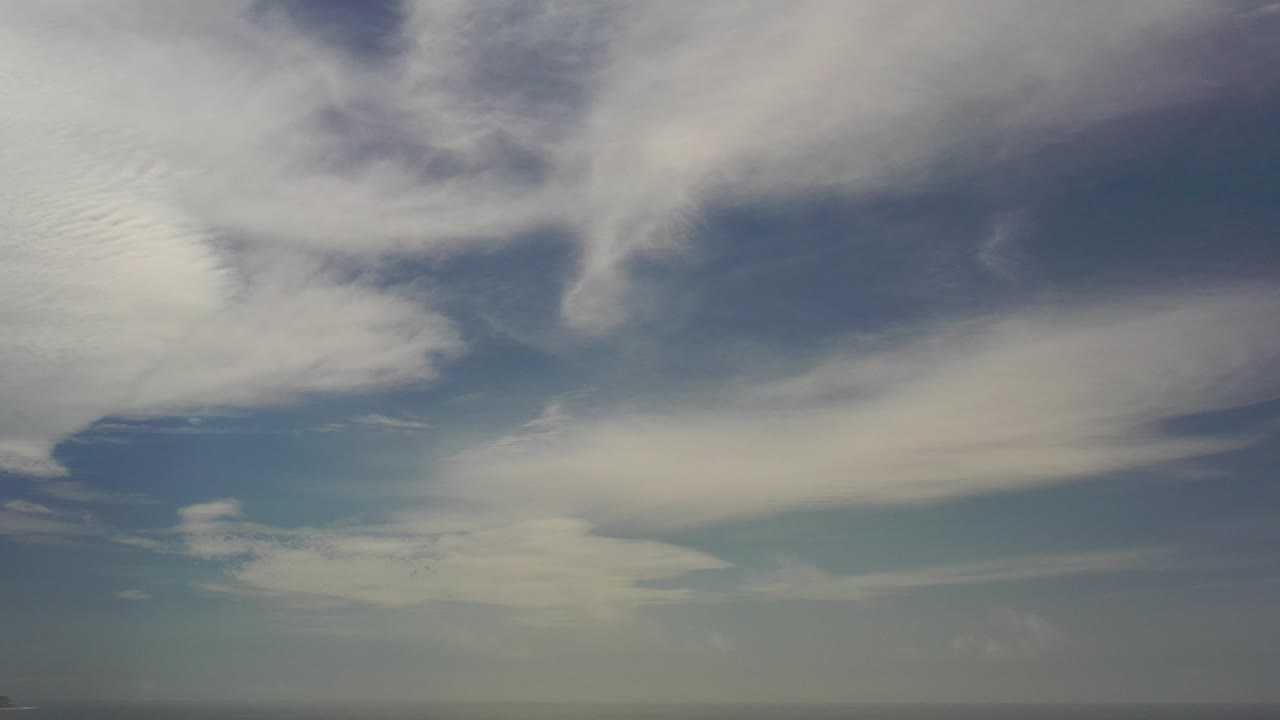 Thin white clouds across a blue daytime sky.