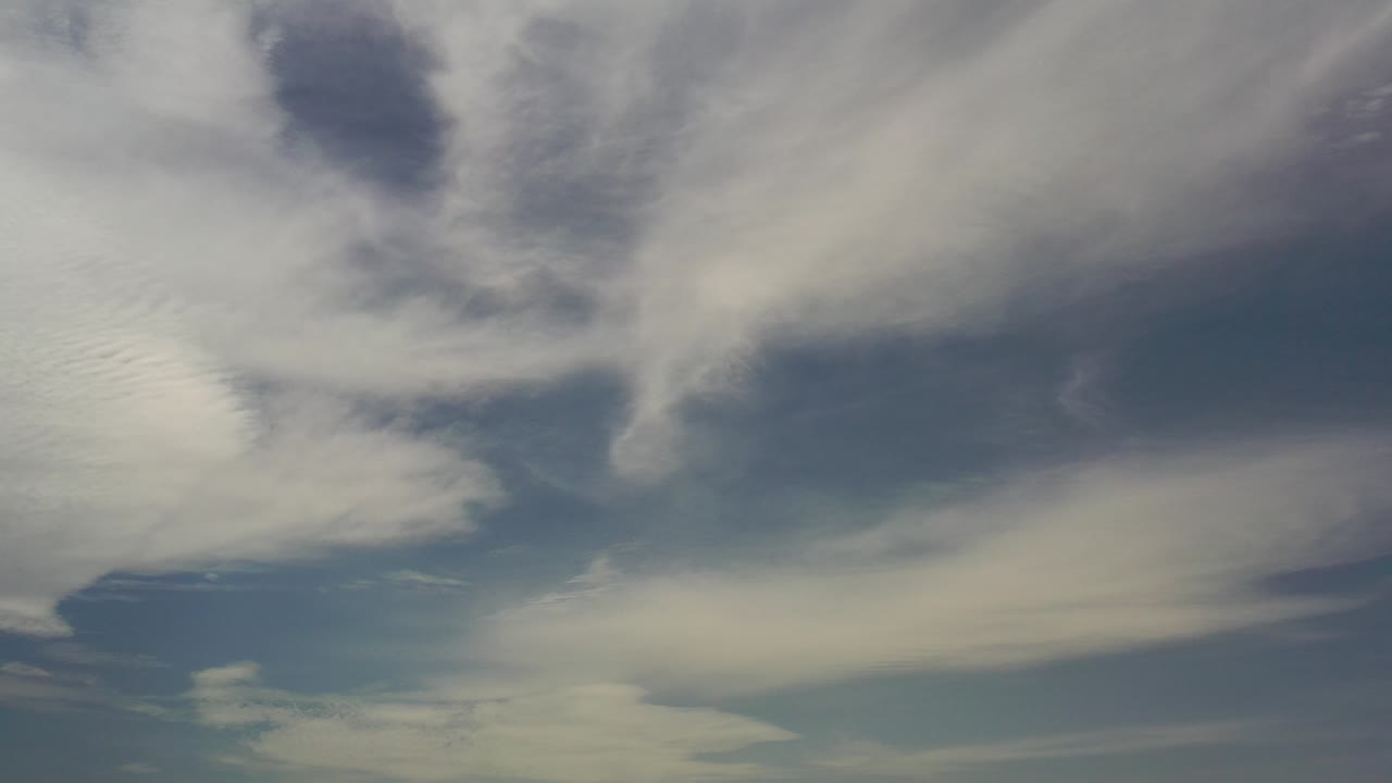 Opening frame of Los Cabos sky footage with broad white cloud bands over muted light blue sky and no visible people.