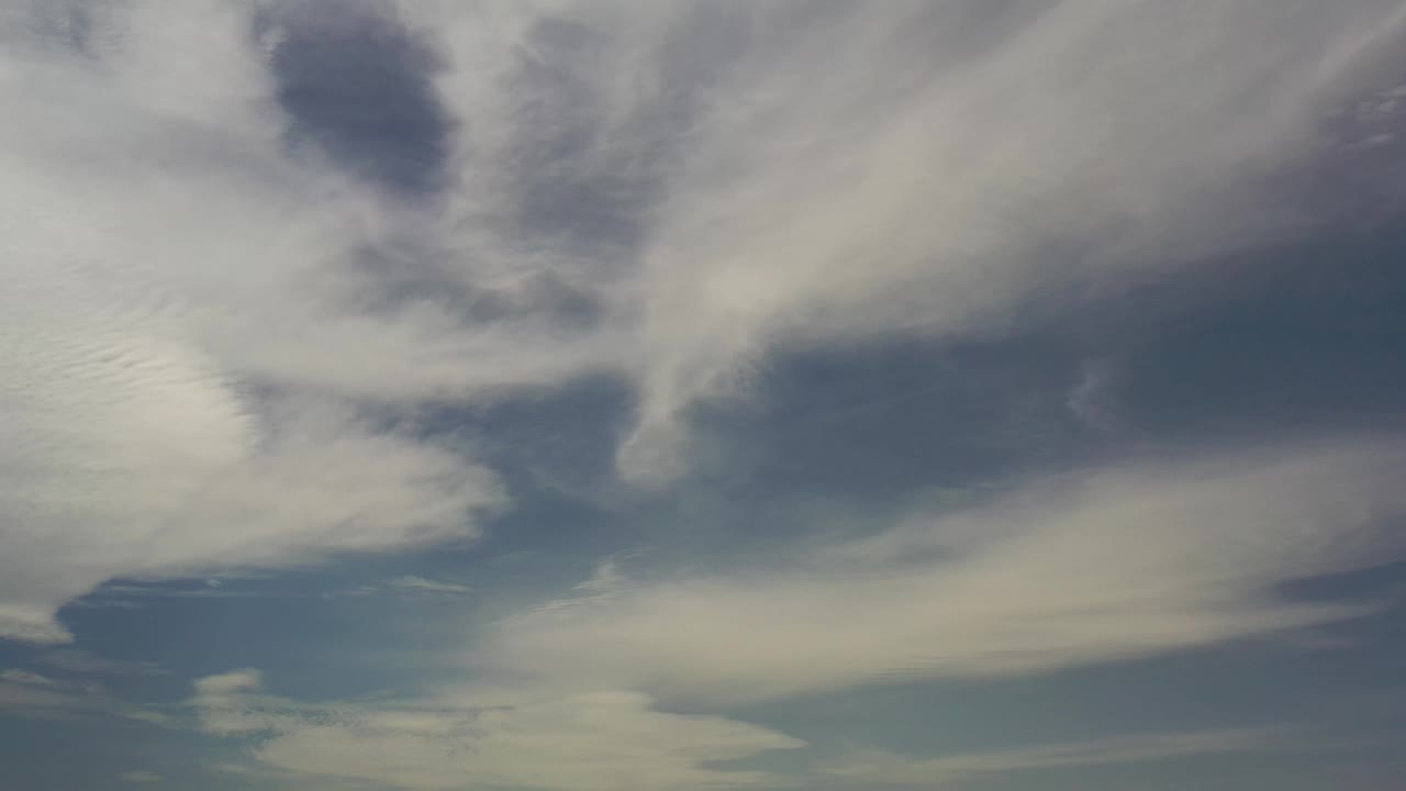 Los Cabos sky frame with a wide pale cloud layer across the lower area and darker blue openings above, with no visible people.
