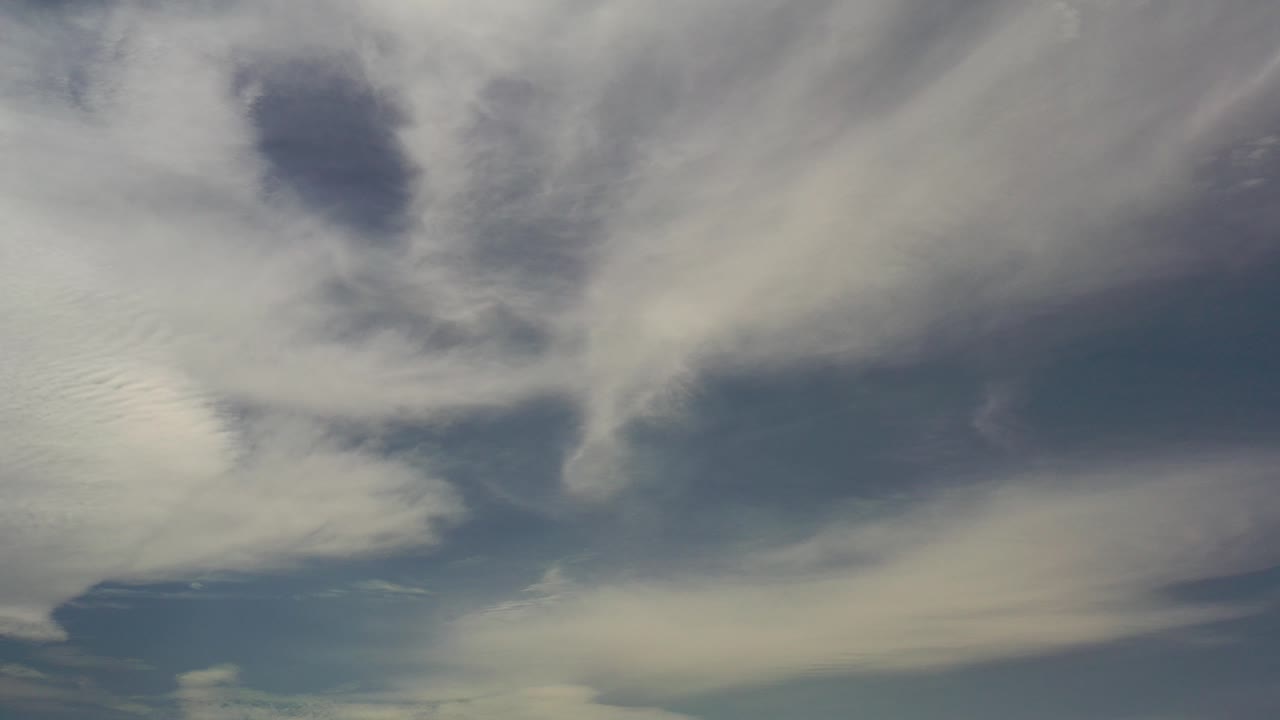White and gray cloud layers fill the Los Cabos sky at the opening moment, with blue gaps and no visible people.