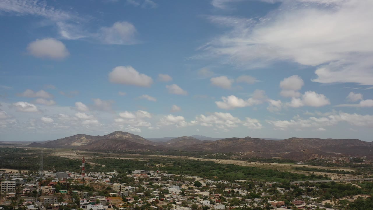 Wide sky over mountains, green valley, and town rooftops.