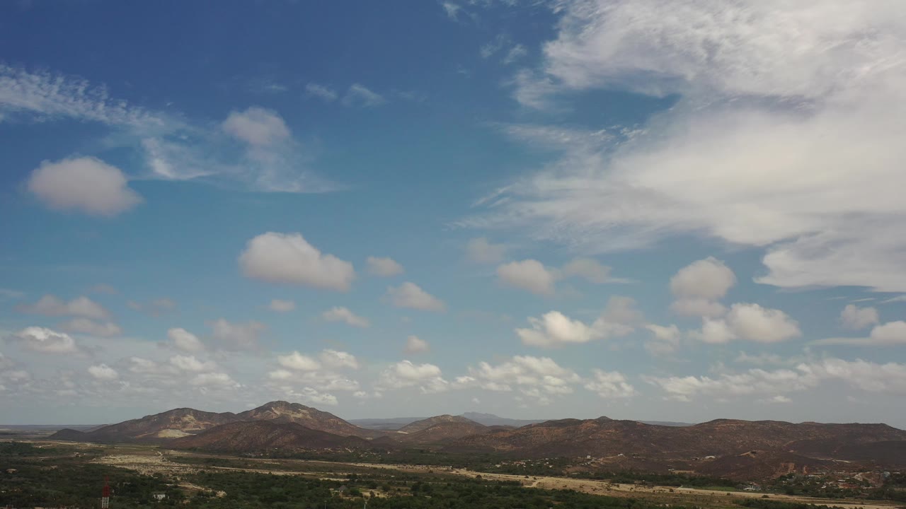Distant brown hills under a bright sky with a large cloud at upper right.