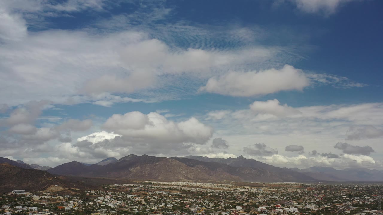 Panoramic mountain skyline with town roofs along the bottom edge.
