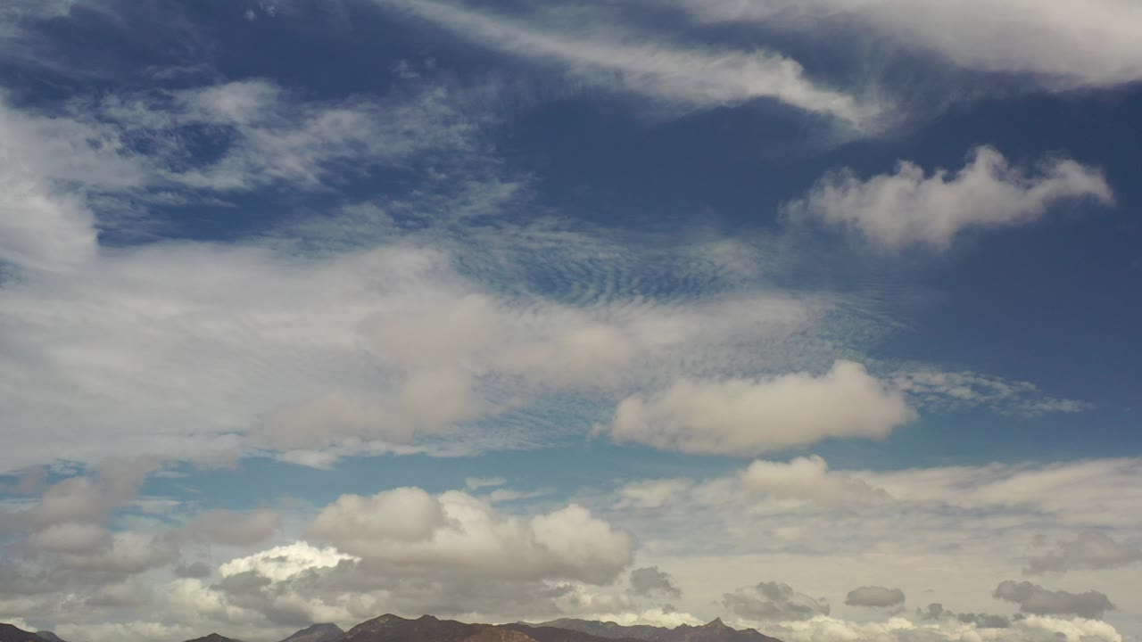 White and gray clouds fill the sky above a thin mountain line.