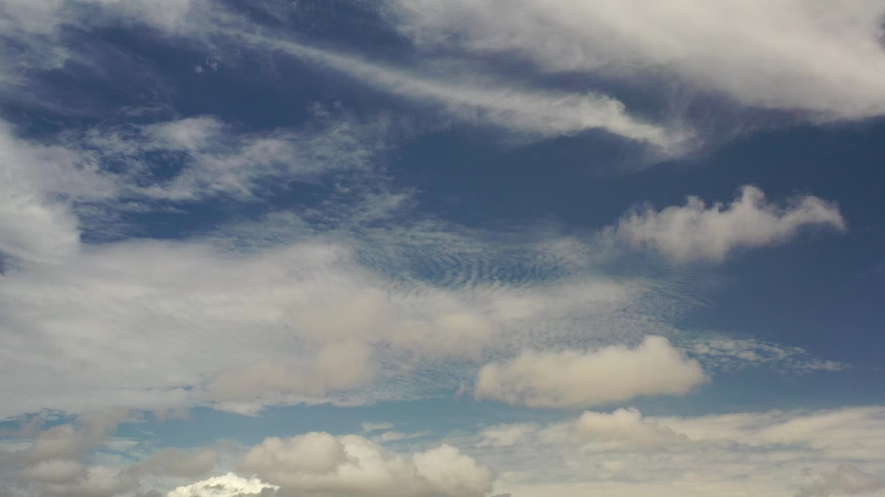 Blue sky over Los Cabos, Mexico with broad white cloud bands and smaller puffs across the lower edge, with no visible people.